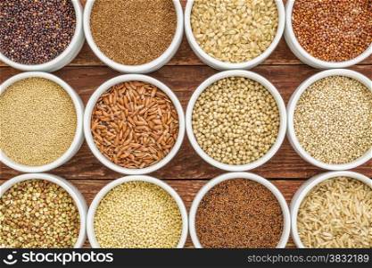 healthy, gluten free grains abstract (quinoa, brown rice, millet, amaranth, teff, buckwheat, sorghum), top view of small round bowls against rustic wood
