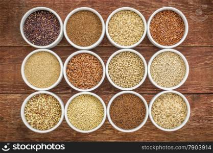 healthy, gluten free grains collection (quinoa, brown rice, millet, amaranth, teff, buckwheat, sorghum) , top view of small round bowls against rustic wood