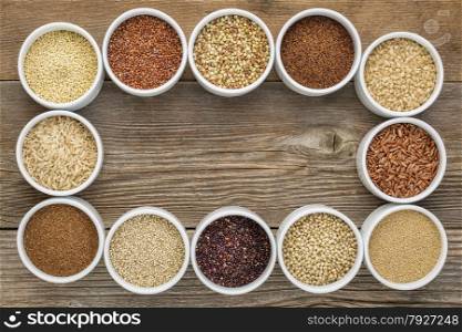 healthy, gluten free grains collection (quinoa, brown rice, millet, amaranth, teff, buckwheat, sorghum) , top view of small round bowls against rustic wood with a copy space