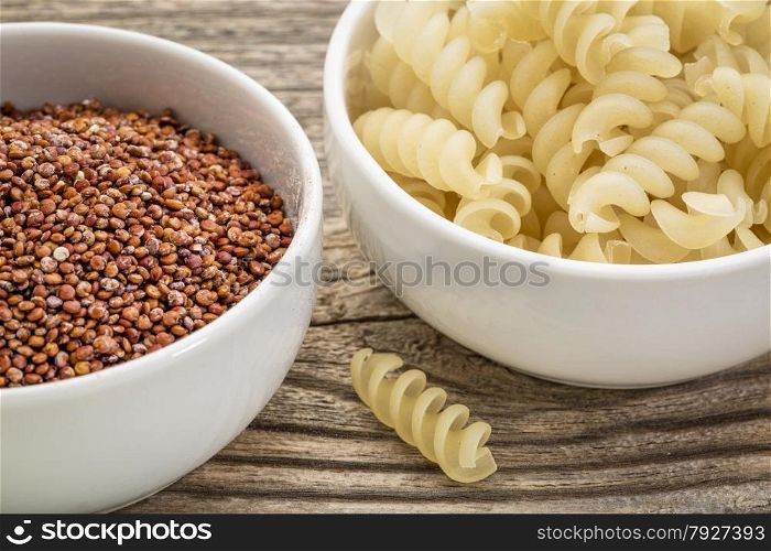 healthy, gluten free quinoa grain and pasta - small ceramic bowls against grained wood