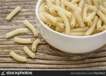 healthy, gluten free quinoa pasta (macaroni) - small ceramic bowls against grained wood