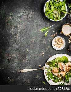 Healthy green diet salad with chicken , Pine nuts and olive oil dressing on dark rustic background, top view, border. Healthy eating or diet food concept
