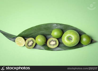 Healthy green fruits on a large leave. Above view with raw food on the greenish kitchen table