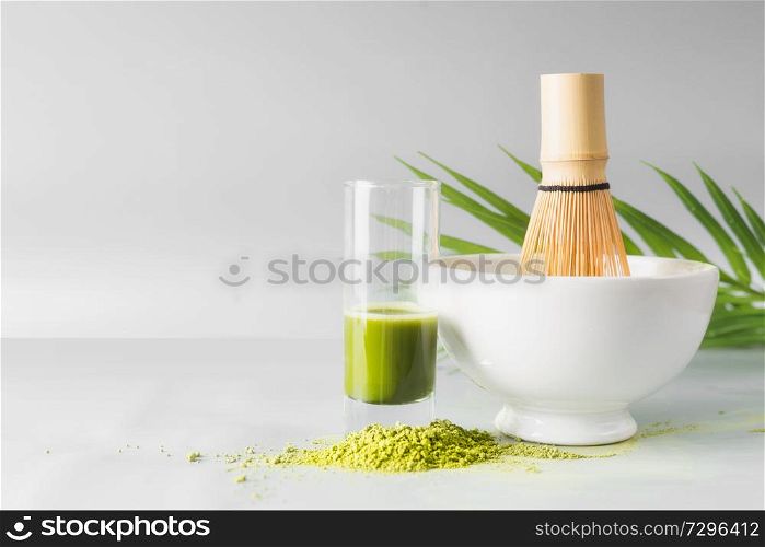 Healthy green matcha espresso in glass standing on table at light gray wall background. Clean eating, detox beverage, dairy food concept. Antioxidant boost drink