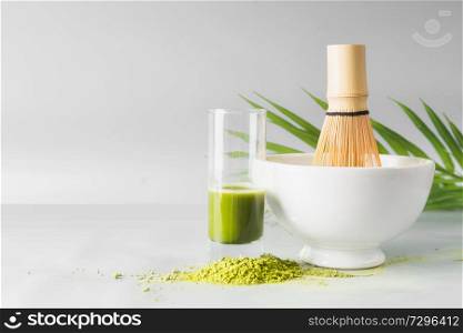Healthy green matcha espresso in glass standing on table at light gray wall background. Clean eating, detox beverage, dairy food concept. Antioxidant boost drink