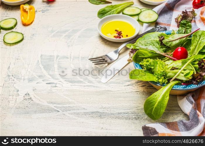 Healthy green salad preparation with dressing and cutlery on white rustic background. Diet eating, Vegetarian or vegan food concept