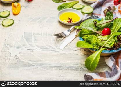 Healthy green salad preparation with dressing and cutlery on white rustic background. Diet eating, Vegetarian or vegan food concept