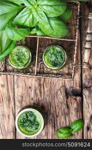 healthy green smoothie with basil. Freshly blended green basil smoothie in glass jar on wooden table