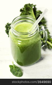 Healthy green smoothie with straw in a jar mug on white background