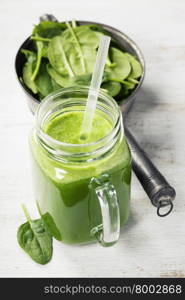 Healthy green smoothie with straw in a jar mug on white background