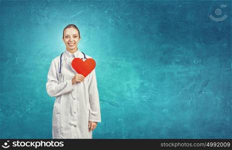 Healthy heart. Young female doctor holding red heart in hands