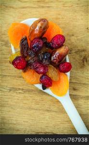 Healthy high fiber food, organic nutrition. Closeup different varieties mix of dried fruits on wooden spoon.