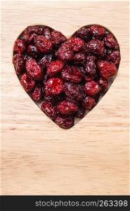 Healthy high fiber food, organic nutrition. Dried cranberries cranberry fruit in shape of heart on wooden surface background