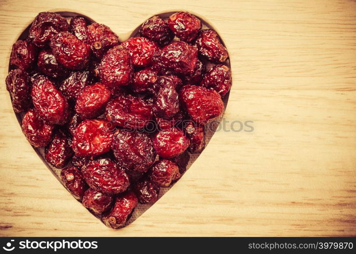 Healthy high fiber food, organic nutrition. Dried cranberries cranberry fruit in shape of heart on wooden surface background