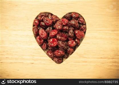 Healthy high fiber food, organic nutrition. Dried cranberries cranberry fruit in shape of heart on wooden surface background