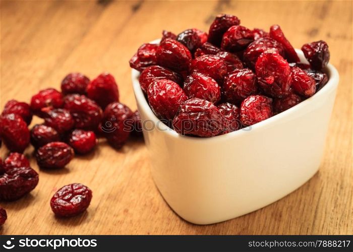 Healthy high fiber foods, organic nutrition. Close up dried cranberries cranberry fruit in bowl on wooden table.
