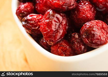 Healthy high fiber foods, organic nutrition. Close up dried cranberries cranberry fruit in bowl on wooden table.