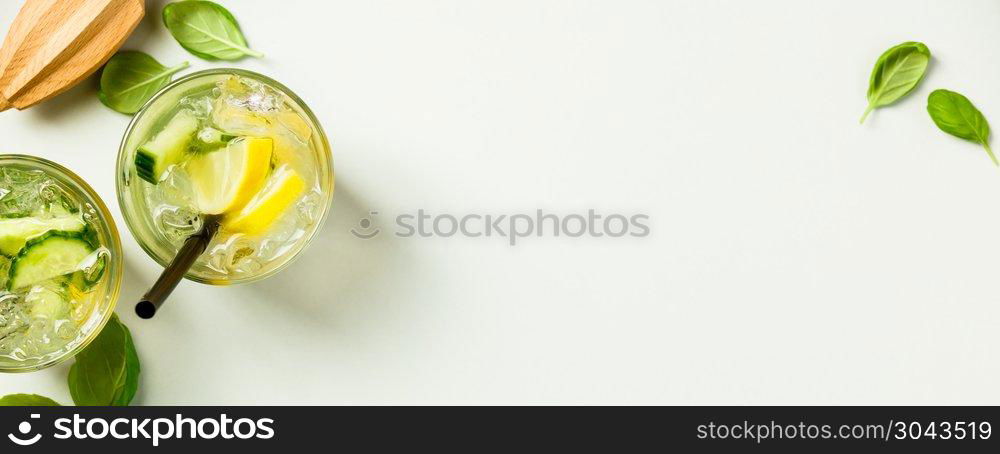 Healthy homemade lemonade with cucumber basil lemon honey and iced water on light blue background. Top view, flat lay