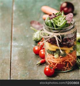 Healthy Homemade Mason Jar Salad with Beans and Veggies - Detox, dieting, vegetarian, vegan, clean eating food concept. Dark green background, selective focus