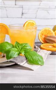Healthy juice from oranges with basil leaves in glass, selective focus