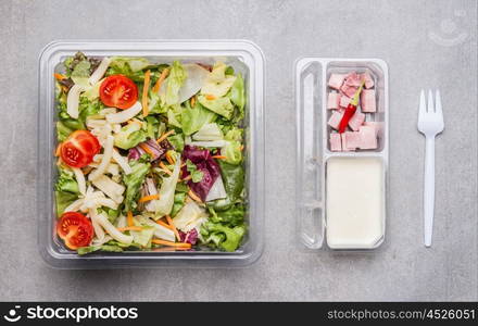 Healthy lettuce salad with cheese ,ham and yogurt dressing in lunch box, top view