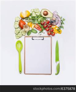 Healthy lifestyle and clean eating concept. Various fresh salad vegetables with cooking spoon and knife around clipboard with blank paper . Copy space for shopping list, dieting plan or menu