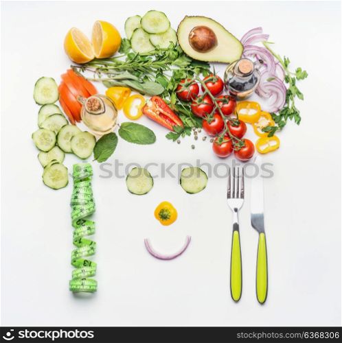 Healthy lifestyle and dieting concept. Friendly face made of various salad vegetables, cutlery and measuring tape on white desk background, top view. Clean food and vegetarian eating