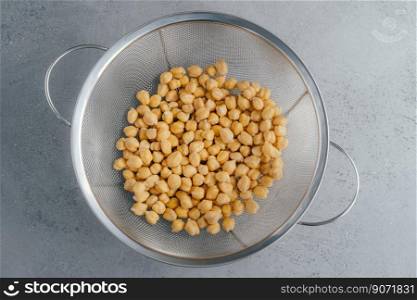 Healthy lifestyle and dieting concept. Top view of garbanzo or chickpeas in sieve. Organic product. Making vegetarian salad. Uncooked food