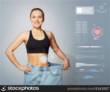 healthy lifestyle and technology concept - young slim sporty woman in large size pants showing weight loss result. young slim sporty woman in large size pants