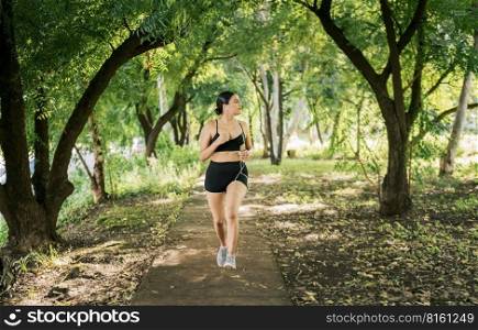 Healthy lifestyle concept of a woman jogging in a green park, Sporty young woman running in a park. Girl running in a park while listening to music, Lifestyle of sporty woman running in a park