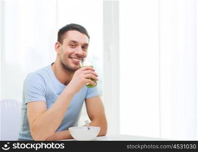 healthy lifestyle concept - smiling happy man having breakfast at home and drinking green juice or smoothie. happy man having breakfast at home