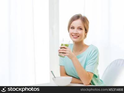 healthy lifestyle concept - smiling happy woman having breakfast at home and drinking green juice or smoothie. happy woman having breakfast at home