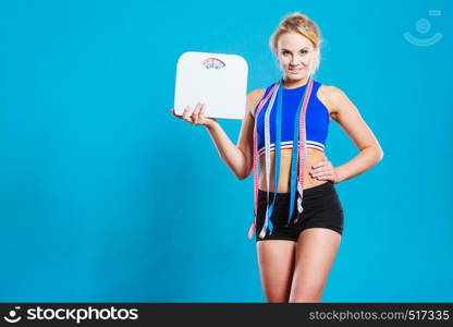 Healthy lifestyle. Fitness woman with many measure tapes holding weight scale studio shot blue background. Fit woman with measure tape with weight scale