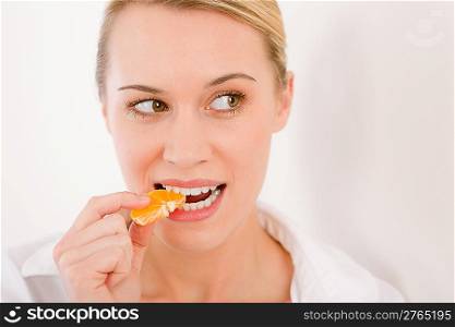 Healthy lifestyle - portrait of woman biting tangerine slice on white background