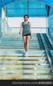 Healthy lifestyle sports woman walking on stairs of city bridge