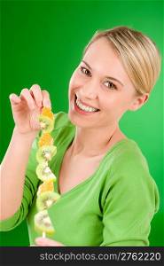 Healthy lifestyle - woman eating kiwi and orange on stick