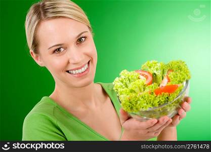Healthy lifestyle - woman holding vegetable salad on green background