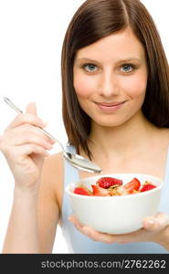 Healthy lifestyle - young woman eat strawberry cereal in bowl