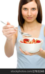 Healthy lifestyle - young woman eat strawberry cereal in bowl