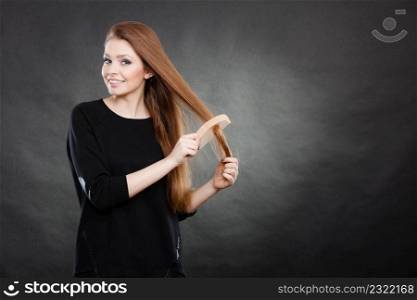 Healthy look concept. Girl combing brushing her hair by using wooden comb. Young woman taking care of everyday hygiene and natural beauty.. Long haired woman combing her hair.