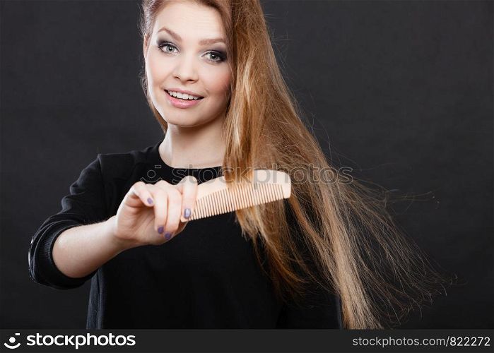 Healthy look concept. Girl combing brushing her hair by using wooden comb. Young woman taking care of everyday hygiene and natural beauty.. Long haired woman combing her hair.
