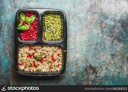 Healthy lunch box with salad, pomegranate and pistachios nuts on rustic background, top view, place for text