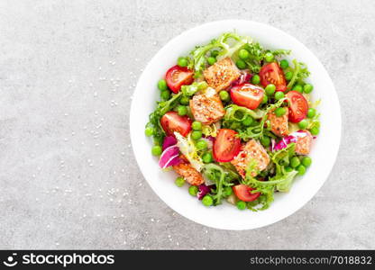 Healthy lunch vegetable salad with baked salmon fish, fresh green peas, lettuce and tomato. Top view