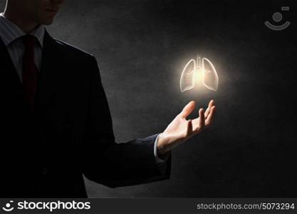 Healthy lungs and breath . Male hand on dark background holding lungs symbol