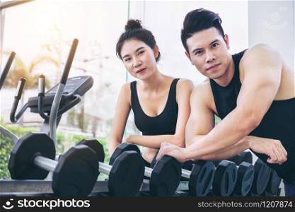 Healthy man and woman doing weight training in gym fitness center. Bodybuilding concept.. Healthy man and woman doing weight training in gym