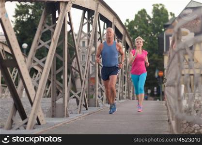 healthy mature couple jogging in the city at early morning with sunrise in background