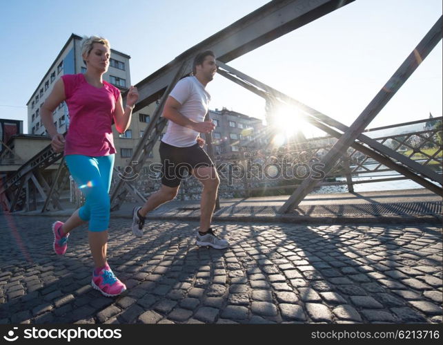 healthy mature couple jogging in the city at early morning with sunrise in background