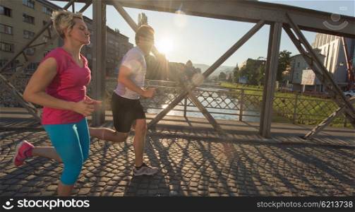 healthy mature couple jogging in the city at early morning with sunrise in background