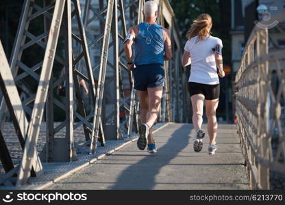 healthy mature couple jogging in the city at early morning with sunrise in background