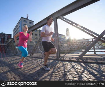 healthy mature couple jogging in the city at early morning with sunrise in background